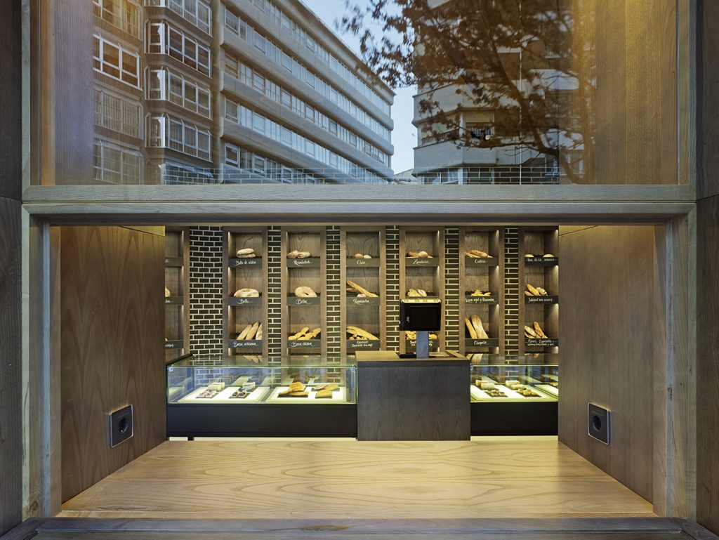 Barra de degustación desplegada con enchufes para móviles y portátiles en diseño interior de Panadería Carnoedo