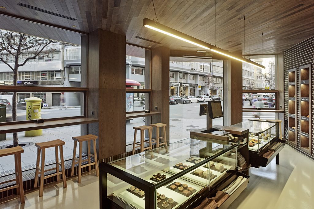 Vista al exterior con barras de degustación en diseño interior de Panadería Carnoedo