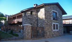 Fachada, torreón y balconada en casa unifamiliar de piedra