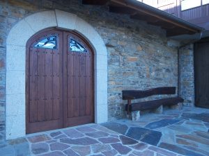 Puerta de madera y banco-traviesa en casa de piedra