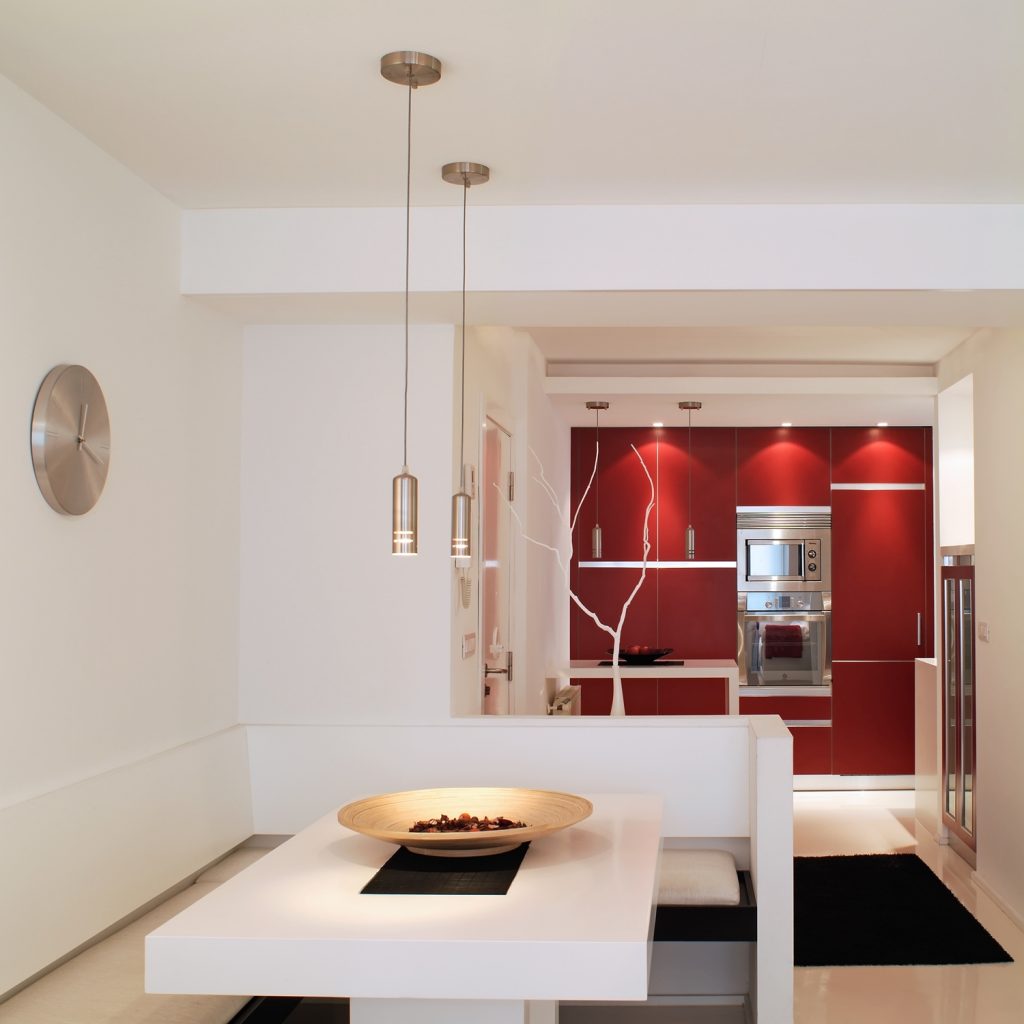 Diseño interior de piso en Galicia. Mesa comedor y bancos con cocina al fondo