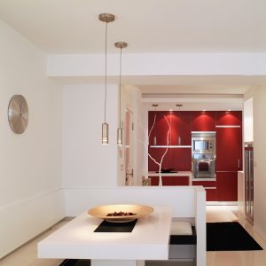 Diseño interior de piso en Galicia. Mesa comedor y bancos con cocina al fondo