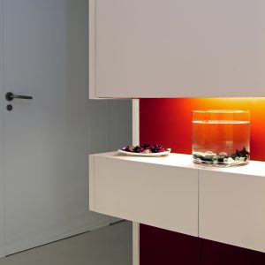 Diseño interior de piso en Galicia. Espacio decorativo con cajones, pintado en el rojo utilizado en toda la vivienda