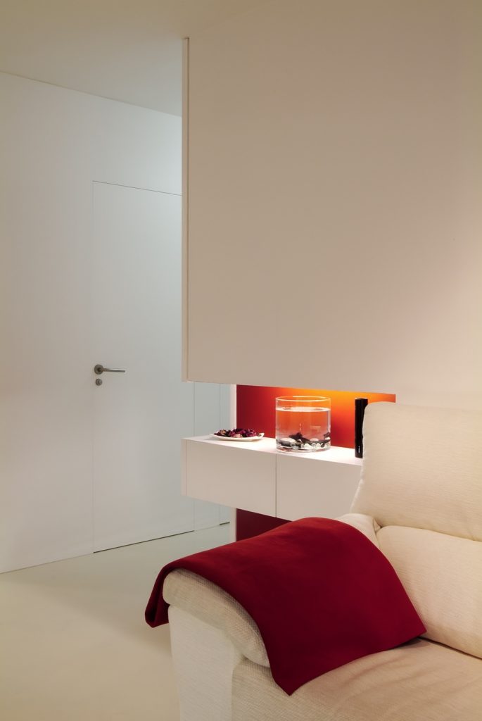 Diseño interior de piso en Galicia. Espacio decorativo y puerta baño al fondo. Interesante la forma de integrar las puertas, sin guarnición y totalmente enrasadas con el paño del pasillo