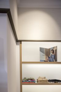 Remates superiores con perfiles metálicos lacados efecto latón en diseño interior de tienda de moda de mujer Jonathans